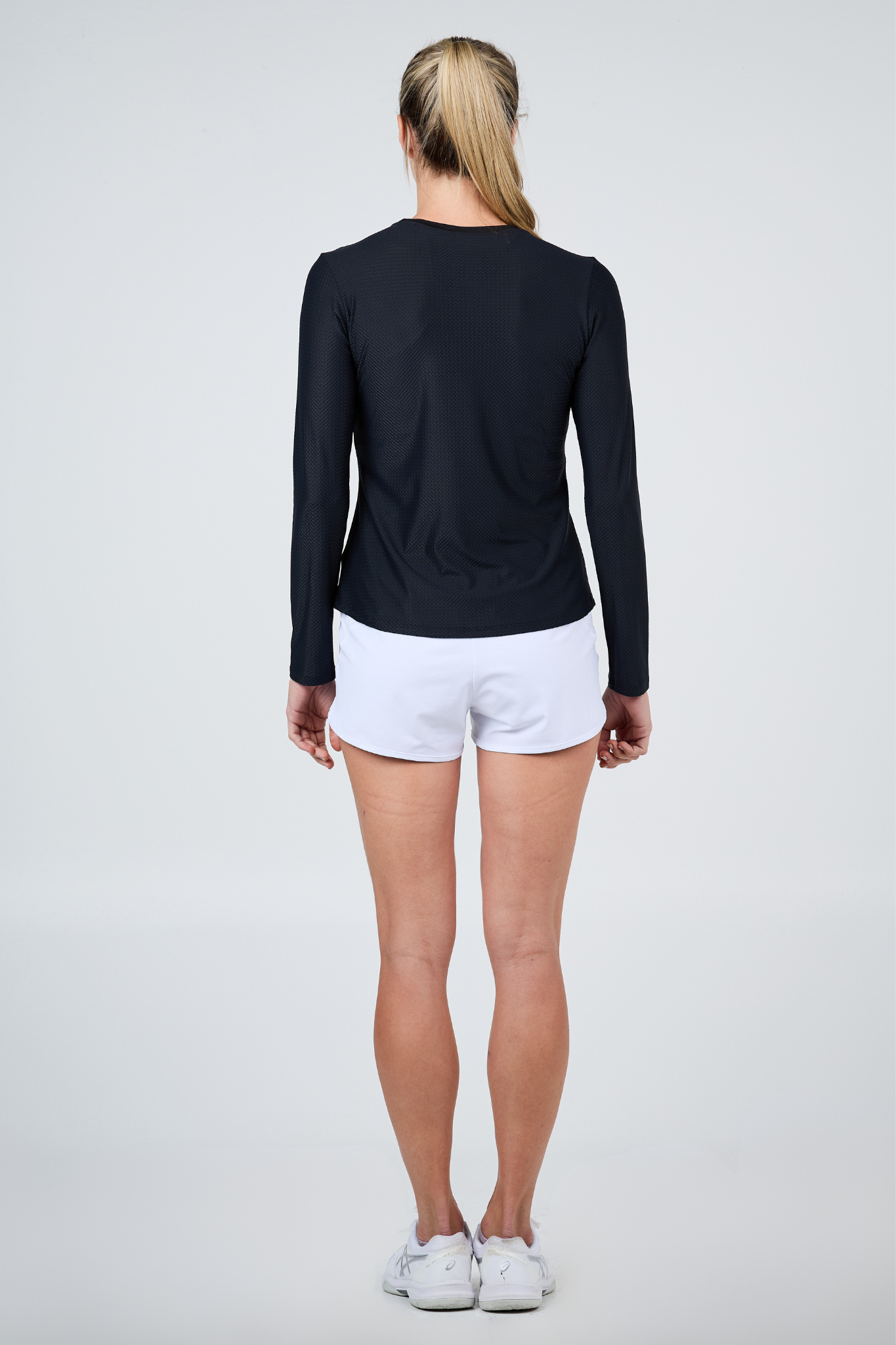 Women's Staples Mesh Long Sleeve Tennis Top in Black by Sofibella, back view on model