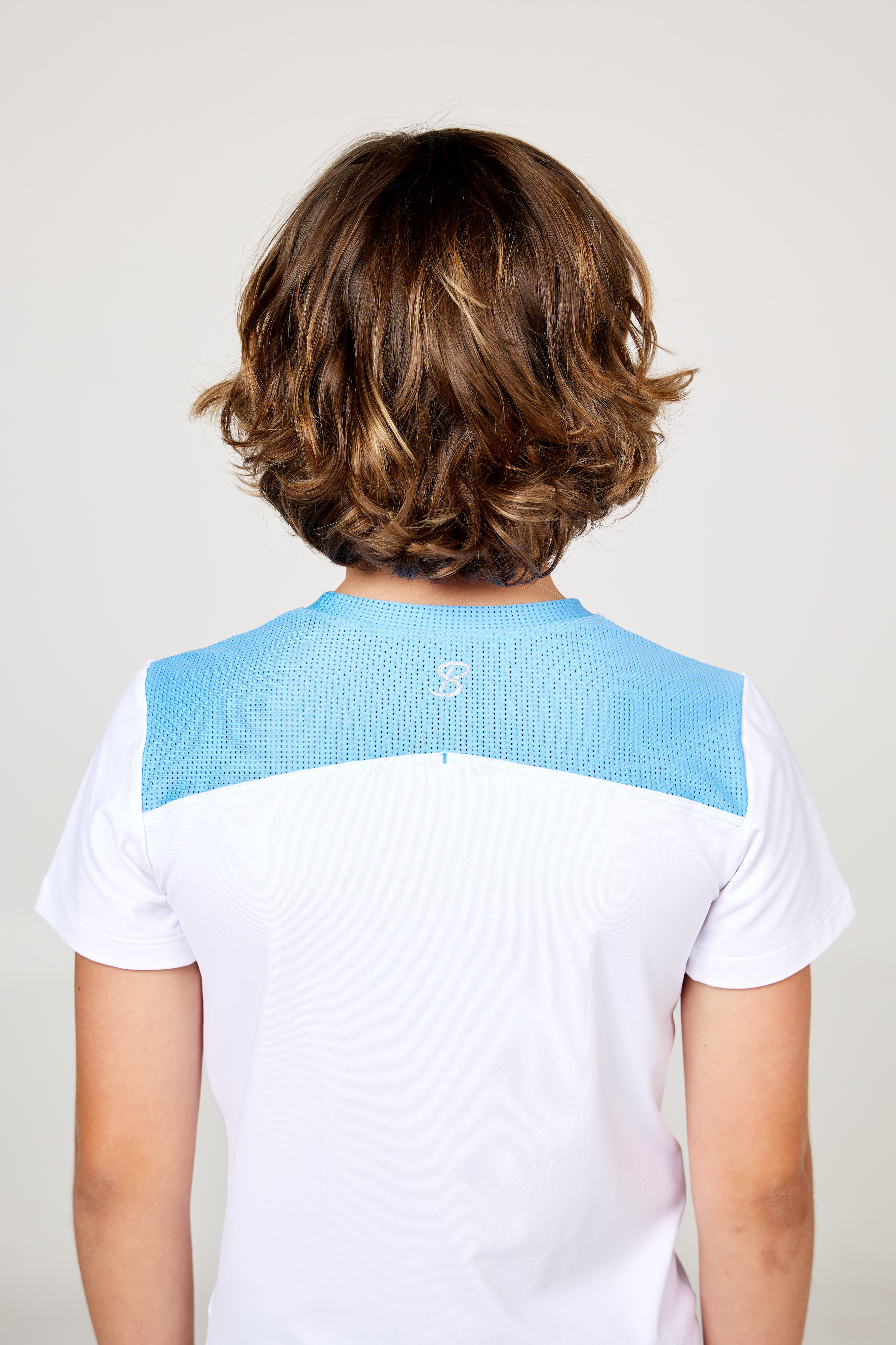 White boys' short sleeve tennis top by Sofibella, back view on model