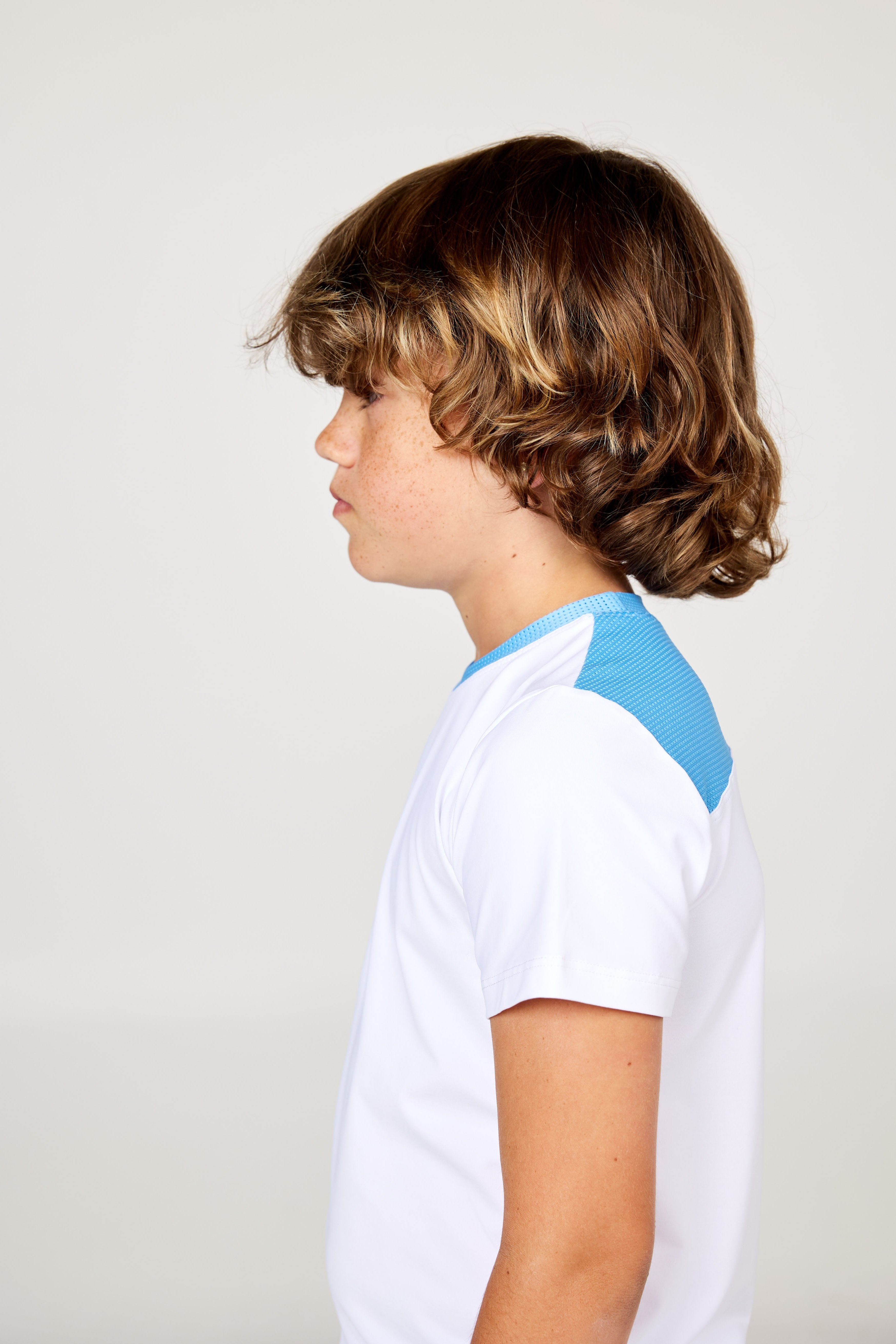 White boys' short sleeve tennis top by Sofibella, side view on model