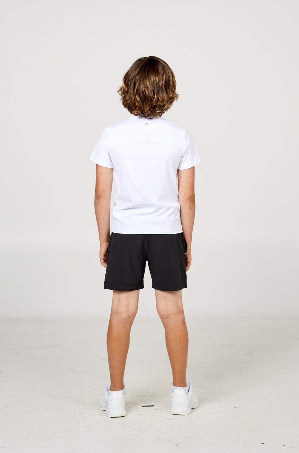 White boys' short sleeve tennis top by Sofibella, back view on model